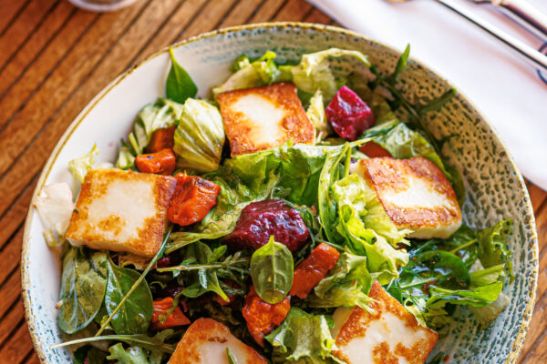 A colorful salad of mixed greens topped with golden-brown cheese squares.