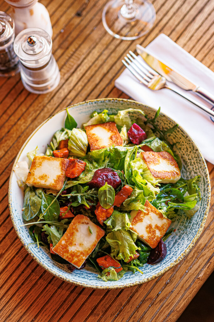 A colorful salad of mixed greens topped with golden-brown cheese squares.