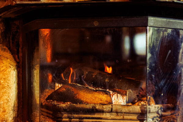 A glass-enclosed fireplace with burning logs, set against a stone surround.