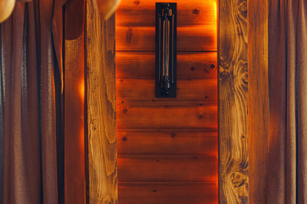 A rustic wooden interior with decorative gourds hanging from the ceiling, a partially set table with wine glasses, and warm ambient lighting.